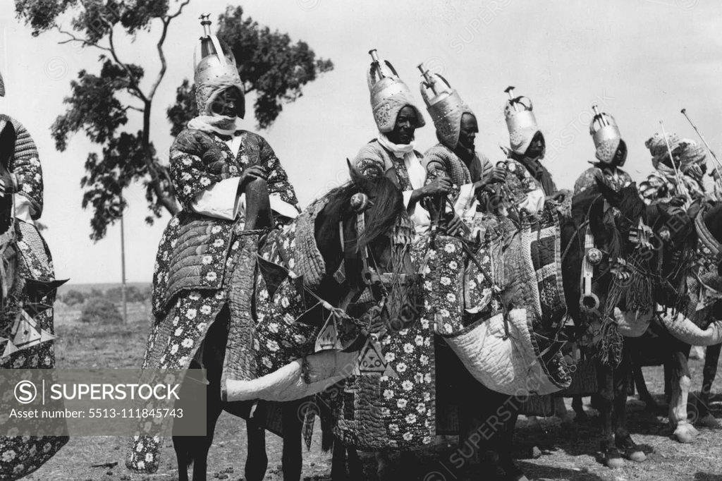 Stock Photo: 5513-111845743 The Queen In Northern ia -- These tribesmen presented a striking picture in their brightly coloured, quilted costumes of themselves and their horses, and the high golden helmets, as they awaited the Queen's arrival at Kaduna. H.M. The Queen and the Duke of Edinburgh once again received a remarkable welcome when they arrived at Kaduna, the capital of N. ia. Thousands of mounted tribesmen, many of whom had travelled long distances, filled the streets with a pegeant of color and excitemen