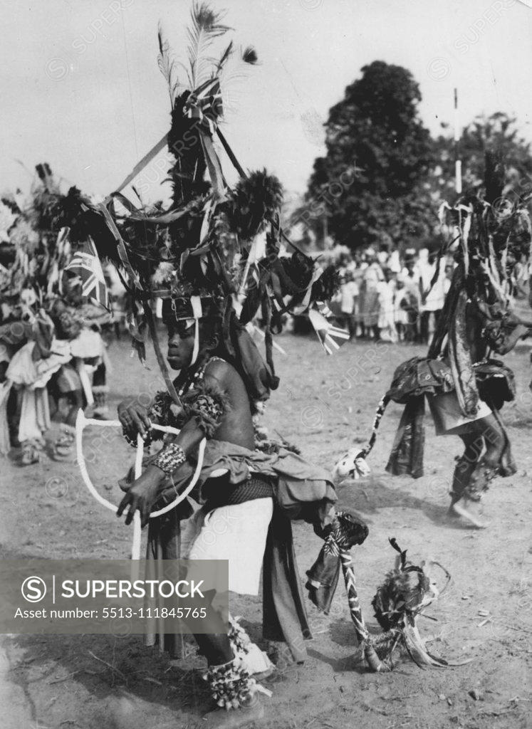 Stock Photo: 5513-111845765 ia Dances For The Queen -- Bedecked with flowers, flags, ribbons and ankle bells and with towering headdress and flowing 'tail', a native dancer performs for the Queen during her visit to Port Harcourt on her ian tour. February 23, 1955. (Photo by Reuterphoto).;ia Dances For The Queen -- Bedecked with flowers, flags, ribbons and ankle bells and with towering headdress and flowing 'tail', a native dancer performs for the Queen during her visit to Port Harcourt on her ian tour.