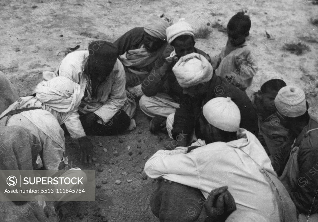 Stock Photo: 5513-111845784 Arabs Of Libya, Unwilling To Return To Italian Domination, Request A Plebiscite -- Men of the Senussi tribe engaged in playing a favourite game - with stones. "The Arab people of Libya wish that tyranny shall not determine their destiny by the handing over of Libya a second time to frightful Italian oppression", said Mansur Kadana, Vice-President of the Committee for the defence of Tripolitania and Cyrenaica, in a statement containing a request for a plebiscite to be made in Libya. These picture