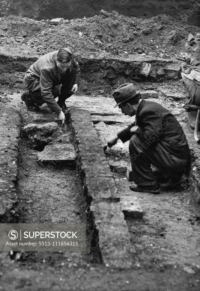 Stock Photo: 5513-111856315 Delving For Mediaeval Crypt Beneath St. Bride's - Charge hand, Mr. F. Beasley (right) of Stepney, and Mr. S. Thomas of Poplar, photographed during excavations at St. Bride's for the mediaeval crypt. An 18th century coffin and parts of a skeleton have been unearthed during excavations to find a mediaeval crypt beneath St. Bride's Church, Fleet Street, damaged by bombs in 1940. February 21, 1952. (Photo by Fox Photos).;Delving For Mediaeval Crypt Beneath St. Bride's - Charge hand, Mr. F. Beasley (