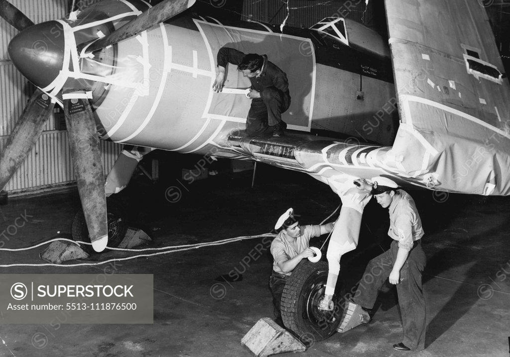 Stock Photo: 5513-111876500 Naval Airman E. Rowe (on wing) and Petty Officers J. Tebby and S. Pearson (RN) taping up all openings in the fuselage prior to it being spayed with a plastic sealing solution. The navy is placing in "mothballs" a number of Firefly and Sea Fury Naval aircraft because of the new planes that are to go into service with the Navy in the near future (Sea Venom Jets and Fairy Gannett aint-sub aircraft). It would be too expensive to maintain these unwanted planes. October 17, 1955. (Photo by Leyden). ;
