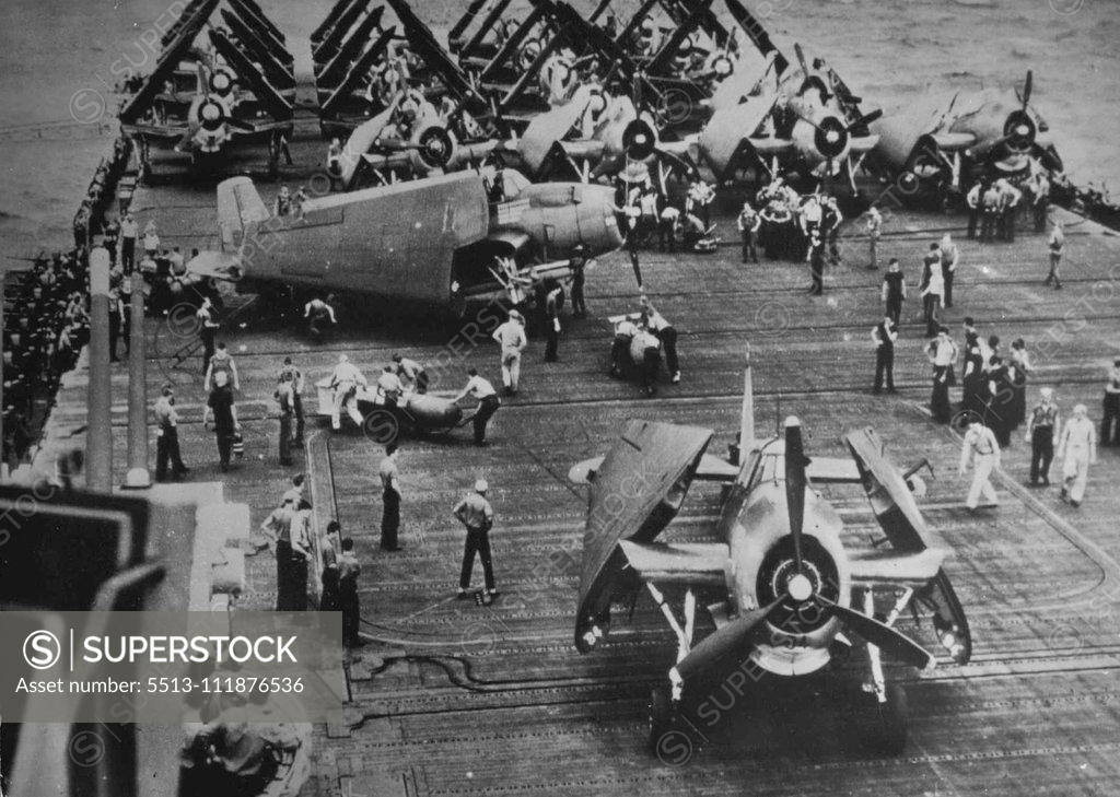Stock Photo: 5513-111876536 Loading U.S. Torpedo Bombers For Strike Against Japanese -- Torpedoes are loaded aboard an Avenger bomber, which is about to take off the flight deck of a U.S. Navy aircraft carrier for a strike against the Japanese in the Pacific. Other planes, part of the Navy's Carrier Air Group Two, stand ready on the deck with wings still folded to save space. Carriers like this one were part of the hard hitting American and Australian naval forces which, in dealt simultaneous battles late in October, 144,