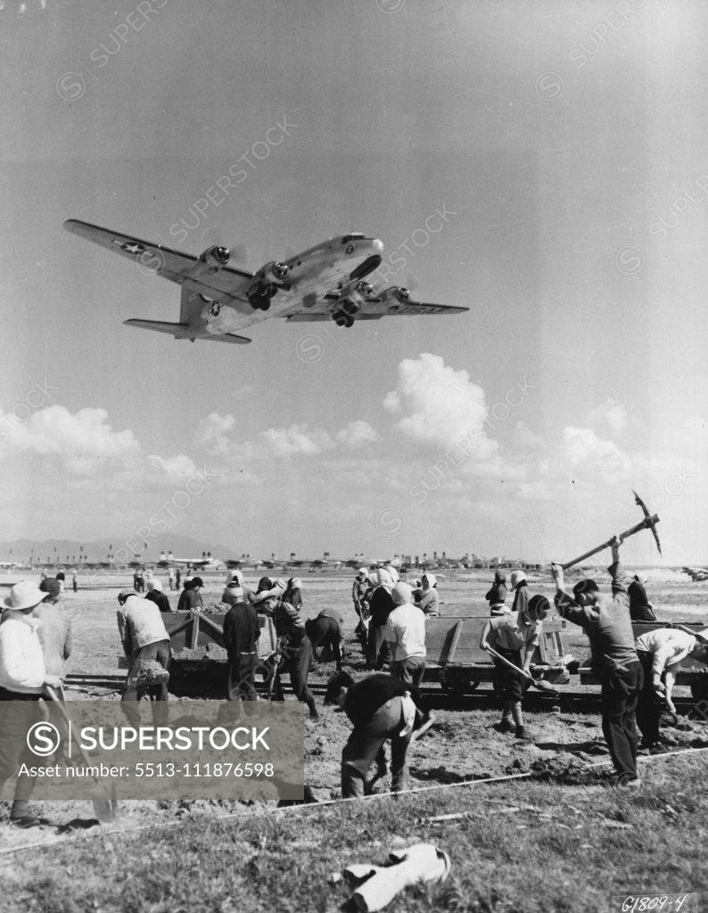 Stock Photo: 5513-111876598 Apathetic Laborers -- An Air Base in Japan-As a huge C-54 Skymaster of the 315th Air Division (Combat Cargo) roars overhead, Japanese laborers continue with their work of runway construction, completely oblivious of the cargo-carrying giant above them. The sight of Far East Air Forces planes taking off and landing has become so commonplace that workers seldom bother to look up at them. August 9, 1951. (Photo by U.S. Air Force Photo).;Apathetic Laborers -- An Air Base in Japan-As a huge C-54 Skym