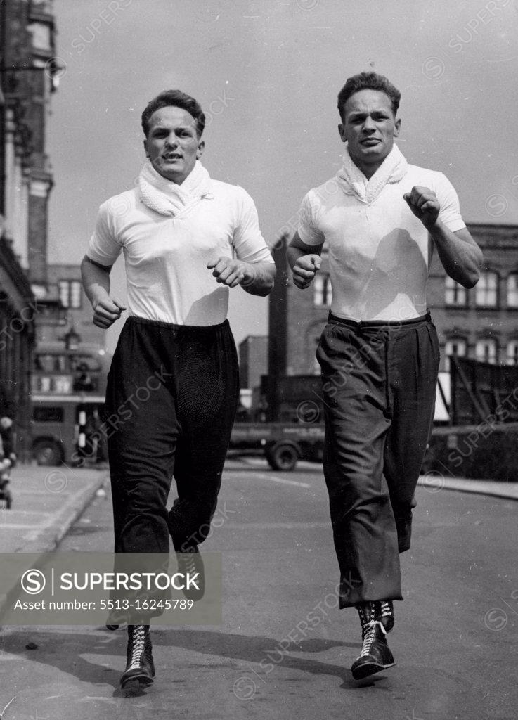 Stock Photo: 5513-16245789 They'll Knock 'Em From The Old Kent Road -- Henry Cooper (on left) and his twin brother near their Old Kent doing a little roadwork near their Old Kent Road training quarters. Both are heavyweights. Jim Wicks, Manager of 20 year old boxer Henry Cooper, has refused an offer of $5,000 from film stars Donald Houston and Stanley Baker, for a half-share of the contract of Cooper, who comes from Bellingham, Kent. Henry is the identical twin brother of George Cooper, who is also a boxer. January 10, 1955. (Photo by Reuterphoto)