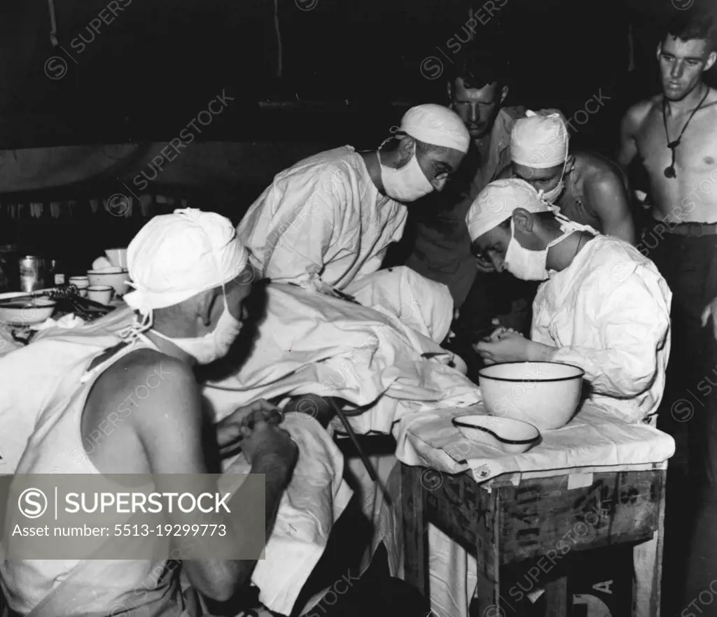 This is at the Headquarters of a mobile surgical team, the most forward medical post in the battle area. An Australian wounded in the head undergoes an operation. Assisting the medical officer are left to right Pte. C. Bingham of Townsville, Qld, Sgt. G. Smith of Edgecliff, N.S.W. and Pte. S. Dow of Mackay Qld. January 13, 1944.