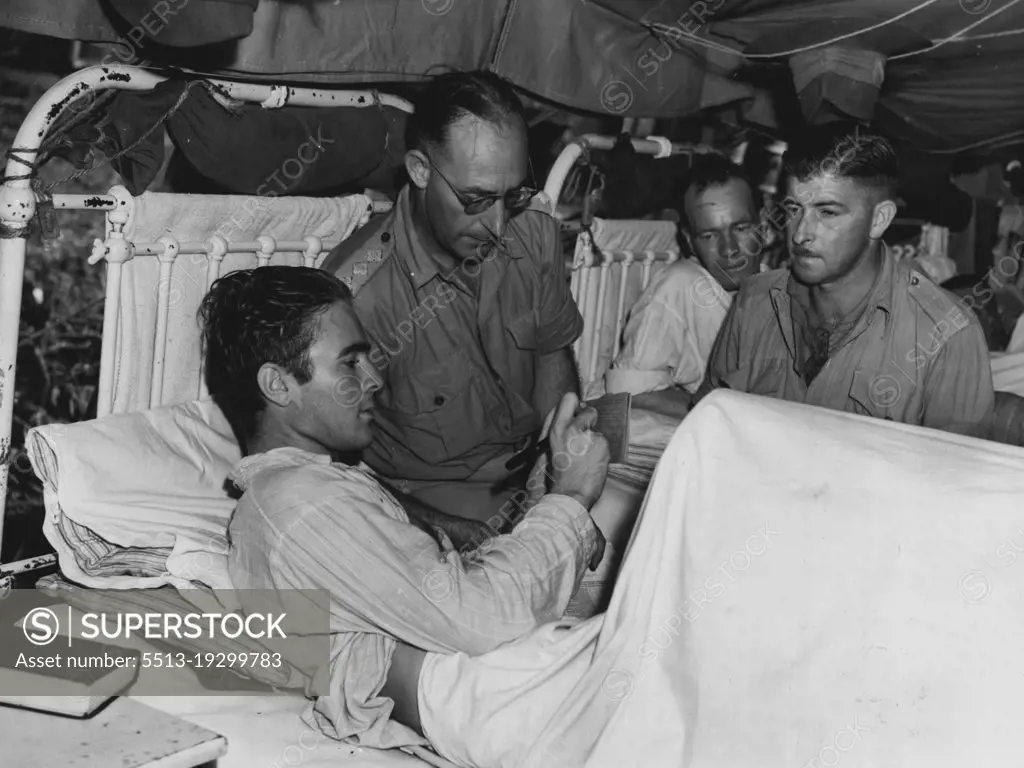 A patient at an Australian General Hospital at Lae casting his vote on the Regerendum. Caption A.J. Bushell of New South Wales is the electoral officer. August 28, 1944.