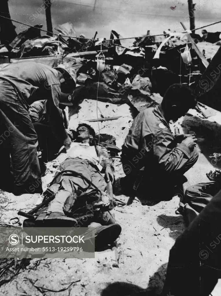 Price Of Invasion... Water and plasma is given a wounded Marine at Eniwetck Atoll in the Marshalls. A Coast Guard combat cameraman caught this dramatic scene as doctors and corpsmen worked under a blazing sun to car for men who fell during the smashing assault. March 12, 1944. (Photo by Official U.S. Coast Guard Photo).