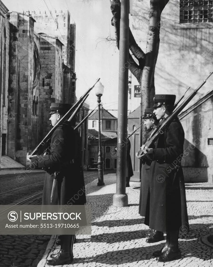 Cities of the World - Lisbon: On one of the old cobble-stoned sidewalks of the ancient Alfama District, these four Portuguese soldiers mount guard outside one of the official buildings. In the background, at left, is part of the district's Cathedral. April 22, 1955. (Photo by United Press).