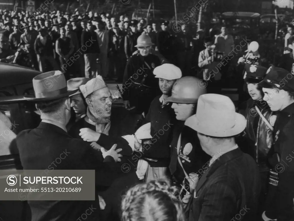 Movie Striker Protests Against Arrest -- A striker tells police what he thinks of being arrested at RKO studio today after he and other pickets refused to heed a court injunction. Limiting the number of pickets at move studio entrances. In background are workers waiting for police to Disband the picket line before entering  the lot. October 24, 1945. (Photo by AP Wirephoto).
