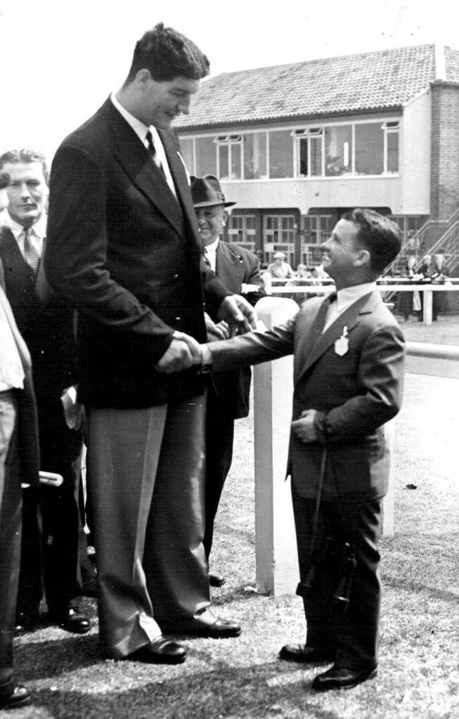 Extremes Meet - At The Races Ewart Potgieter, the giant South African heavyweight boxer who has just arrived in England, shaking hands with Sir Gordon Richards, formerly England's champion jockey and now a trainer when they met at the Brighton race meeting. Potgieter stands 7 feet 2 inches in height. August 04, 1955.