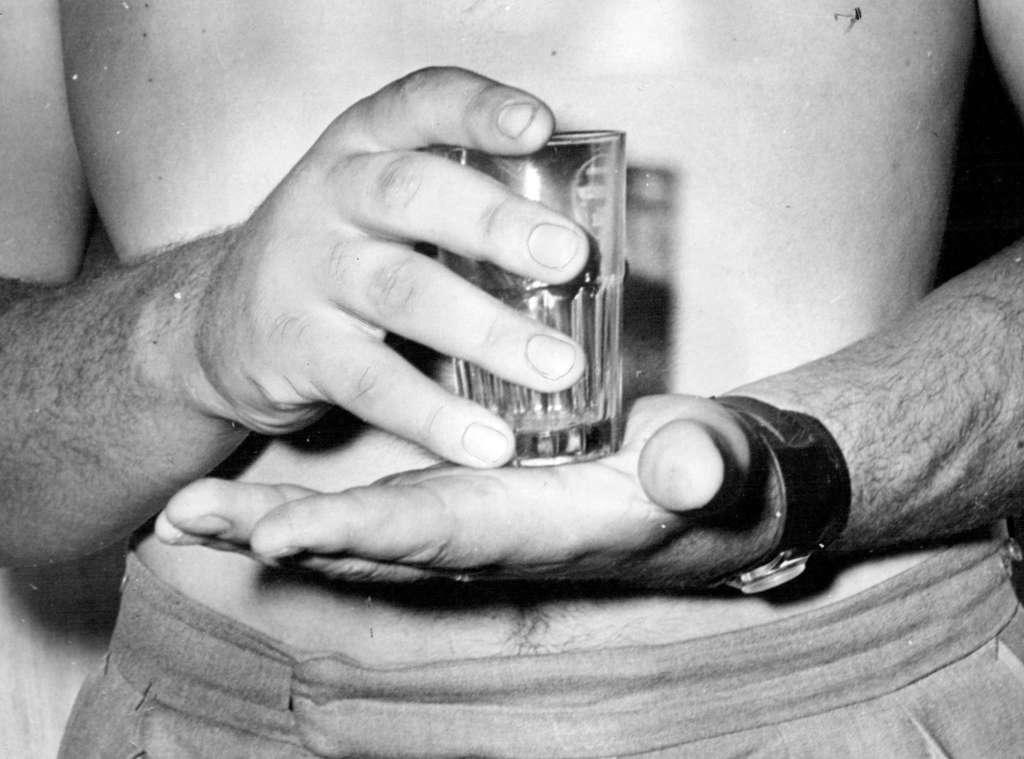 The enormous hands of Ewart Potgieter, South Africa's 7ft 2in boxing giant, are illustrated as he holds a normal a normal-sized drinking glass. Potgieter's fingers resemble fair-sized sausages. From the tip of the middle finger to the joint of the wrist his hand measures nearly 10in and from thump tip across to the other side of the hand the measurement in 8in. December 20, 1954.