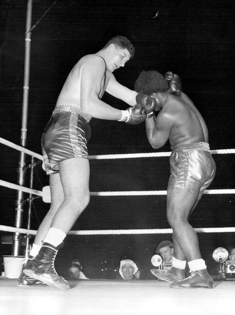 'Pottie' The Giant Stops Jamaican In Six Rounds Simon Templar of Jamaica - looking a pigmy dispite his 16 stone 12 pounds covers up under an attack by South Africa's boxing skyscraper Ewart Potgieter, 7ft. 2in. tall and weighing 22 stone 10 pounds, during their heavyweight contest at the white City stadium, London, tonight (Tuesday). Templar retired at the end of the sixth round. The contest had been scheduled to go 10 rounds. September 13, 1955. (Photo by Reuterphoto).