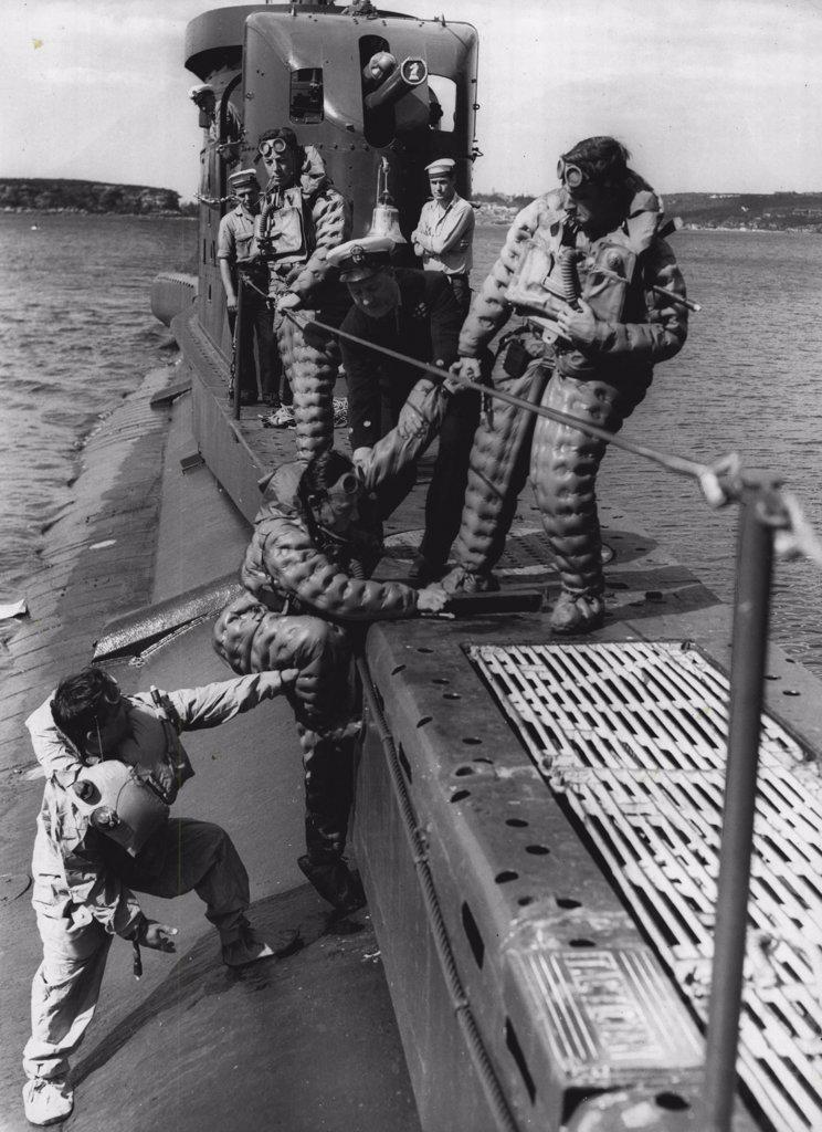 HM Submarine Tactician prepares for ocean voyage to Fiji & New Zealand for exercises with the RNZN & RNZAF.
Testing their escape equipment prior to leaving Sydney tonight. (Tues) These crew members under the instructions of C.P.O Coxswain. A. MacLean on the submarines side.
Watching L/S. I. Gill, P.O. L. O'Gara.. & M (E). I. C. Rayment.
The Tactician is one of three submarines on loan to the Royal Australian Navy and has been engaged in exercises with our squadron.
They can stay afloat for over a week in one of the *****. November 02, 1955. (Photo by Gordon Herbert Short/Fairfax Media).