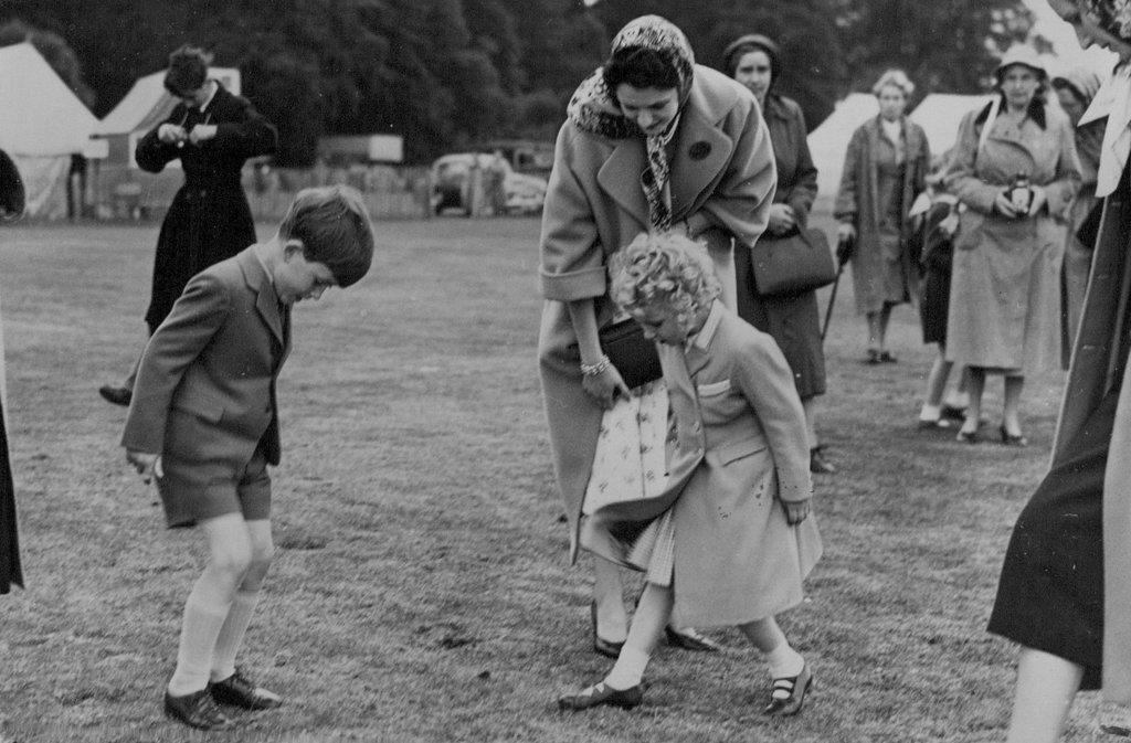 The Royal Family At Polo Tournament -- Following the example of H.M. Queen Elizabeth on the previous day Prince Charles and Princess Anne help to tread down the misplaced turf kicked up by the polo ponies, during the interval.
H.M. The Queen with her two children Prices Charles and Princess Anne attended the Polo Tournament now being held on Smith's Lawn in Windsor Great Park, where they saw the Duke of Edinburgh playing for one of the competing teams. June 15, 1955. (Photo by Sport & General Press Agency, Limited).