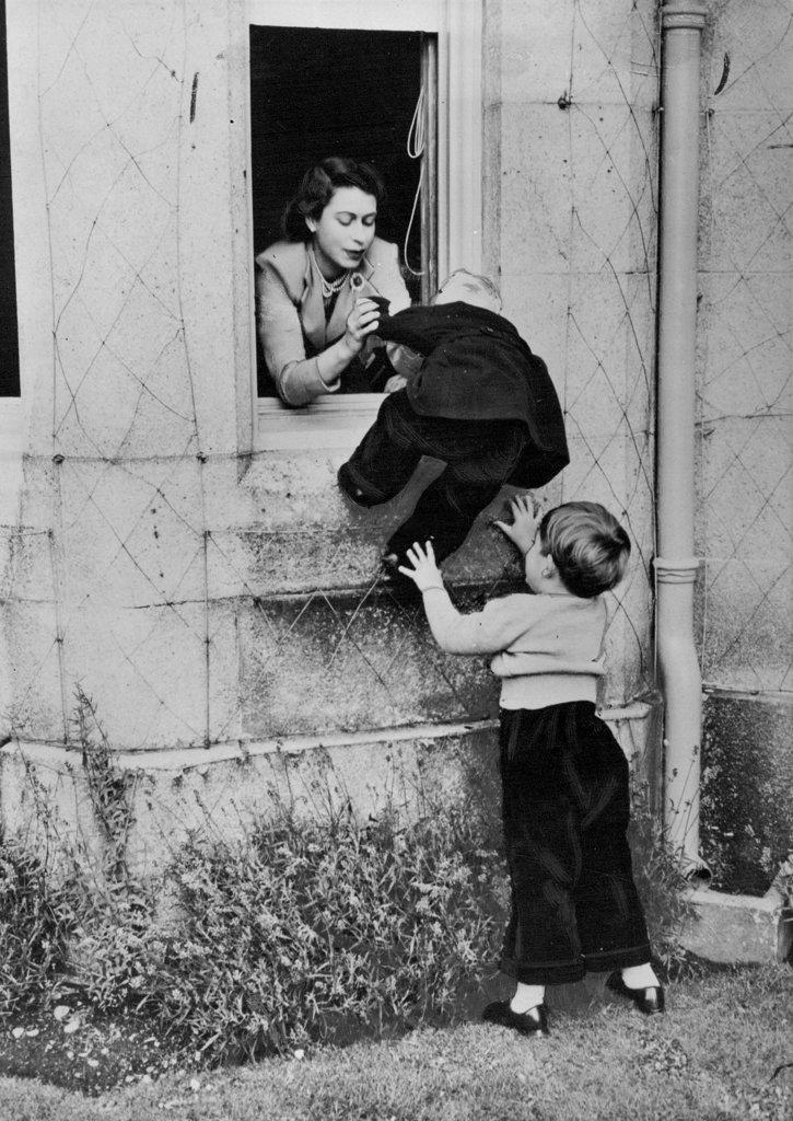 Help For Princess Anne
Princess Anne is assisted by the Queen and Prince Charles to climb in through one of the windows of Balmoral Castle. Prince Charles having climbed up once, jumped down again to help his little sister in her efforts to copy him. May 1, 1953. (Photo by Fox Photos).