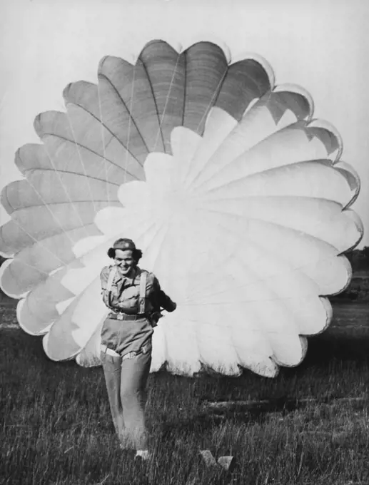 A Nurses' Aid Who Also Flies And Parachutes -- Ann Cutler, 22, of Needham, Massachusetts, in the northeastern section of the United States pulls on the cords of her parachute during training. She not only is a licensed flyer but also a nurses aid, and one of the first candidates for the newly organized Massachusetts Civil Air Patrol's parachute corps of doctors and nurses. November 16, 1942. (Photo by Interphoto News Pictures, Inc.).