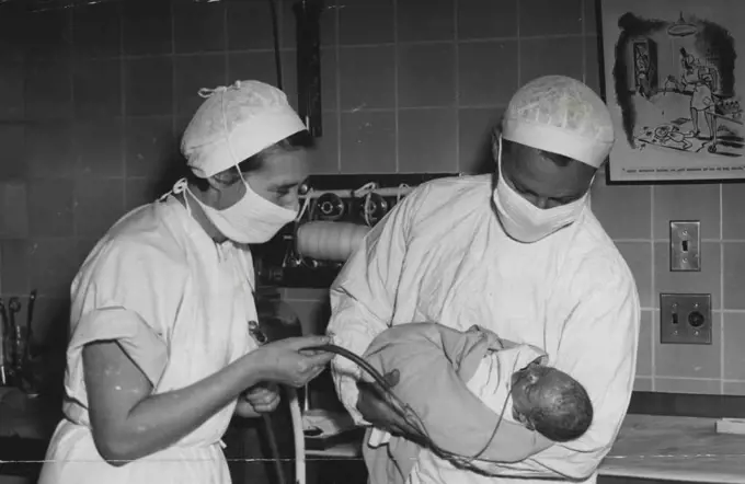 New method which has been saving lives of new born babies, is demonstrated by a doctor and nurse at the King George V Memorial Hospital. The oxygen tube is in the baby's nose. September 29, 1950.