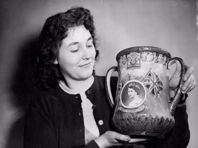 A Coronation Loving Cup, of which only a thousand are being made, is here being admired by 22-year-old Margaret Timmis, a figure artist, at the Royal Doulton Potteries, Burslem, Staffordshire. The Loving Cup, 10½ inches high and hand-painted, was specially designed for the Coronation by Mr. C.J. Noke, Royal Doulton Art Director. On the side shown, it bears a portrait of Queen Elizabeth II framed by a background of Windsor Castle. The decoration also includes the Royal Standard and the Union Jack, the whole being surmounted by the Royal coat of arms. November 18, 1952.