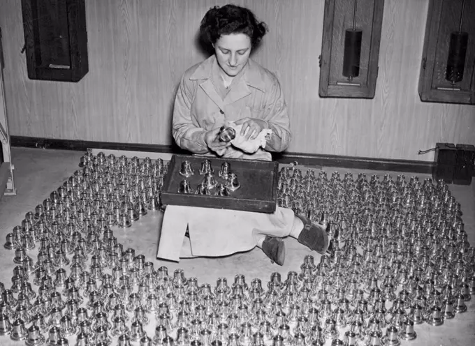 Miniature Bells For Coronation Souvenirs. Miss Doreen Smith, aged 22, of South Norwood, surrounded by hundreds of the miniature bells, which she is cleaning and inspecting. At the foundry of Messrs. Gillett & Johnston, Ltd., in Croydon, miniature bells are being cast from metal obtained from bells which were cast in the time of Queen Elizabeth I. They are perfect replicas and have a Coronation inscription. February 17, 1953. (Photo by Fox Photos).