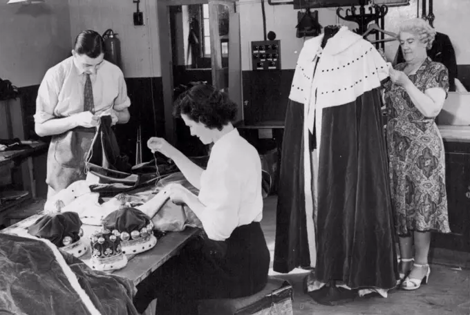 Preparing For The Coronation Working on the collar of a Viscount's robe is Mary McGetting (nearest camera) while Reg. Jackson sews the ham. Mrs. Cross (right) is making the final stitches to a Barons robe. Tailoresses and tailors of one of London's biggest hire outfitters are now busy making sure that The Coronation robes and Coronets which will be hired out and worn by Barons and Viscounts are in good order. The robes, which today cost about £500 - but they can be hired from the big oufitting firms for £25 complete with Coronet. August 26, 1952. (Photo by Sport & General Press Agency, Limited)