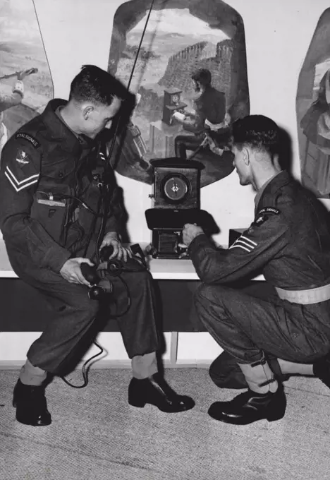 "Signalling Through The Ages" At Radio Exhibition - Part of the Army's exhibit in the show, "Signalling thorough she ages", Cpl. Fulkner (left) of the Royal Signals, with the latest type Infantry 2-way radio-telephone, chats with S.Q.M.S. Oates who is demonstrating a single needle telegraph dating back to 1857, as used by the Army in the Korean War. The latest development in radio and television are to be seen at the National Radio Exhibition which opened at Earls Court today. August 28, 1951. (Photo by Fox Photos).