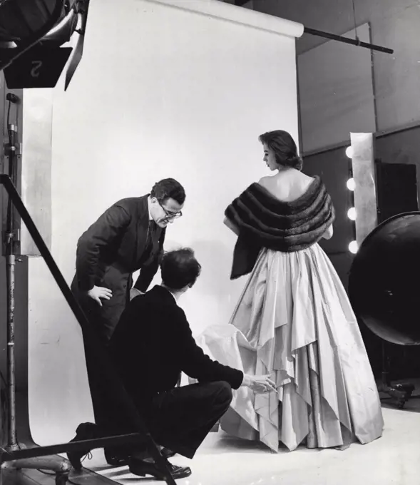 After being fitted for a suit, Elizabeth goes with Peter Langley to West End studio of photographer John Cole, where she is to model a fur stole and strapless, tiered evening dress. May 27, 1953. (Photo by AGSUP Pictures).