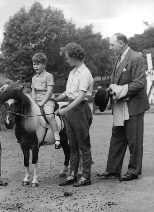 5½-year-old Princes Charles paid a surprise visit to pets corner at the London Zoo. Climax of the visit was a ride on the pony led by Janet, the young lady who is known to many thousands of children as one of the attendants of Pets Corner. On the right, holding Prince Charles coat, is the detected who accompanied the party. Prince Charles has his mother's interest in horses but at the moment at pony's big enough. November 15, 1954. (Photo by Stan Evans, Camera Press).