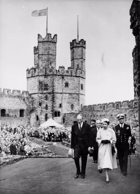 Queen And Duke Visit Caernarvon Castle -- Queen Elizabeth II and the Duke of Edinburgh (right), accompanied by Lord Harlech, constable of caernarvon castle (left), are followed by Sir David Maxwell Fyfe, the Home secretary as they walk through the grounds of the castle, July 10th. The royal standard flies from tower of castle. Forty thousand people roared a welcome to the Queen when she visited ancient Caernarvon Castle today July 10th - the first Queen regnant to enter the Welsh stronghold since King Edward I built it seven centuries ago. On a balcony above Queen Eleanor's gate the Queen came out alone to acknowledge the cheers. It was from this gate 700 years ago that King Edward I held up his baby son, the first Prince of Wales, to the Welsh Chieftains. With the cry: "Eich Dyn" - "Your Man". July 12, 1953. (Photo by Associated Press Photo).