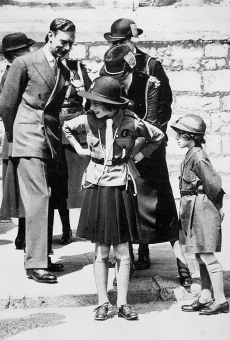 Girl Guides Inspection At Windsor A charming incident during the March Past of the Girl Guides. Out photograph shows Princess Elizabeth having the belt of her uniform adjusted. His Majesty King George VI is looking on. Princess Margaret is seen on the right in the Brownie uniform. This is the first time the Princesses have attended a function in their Girl Guides uniform. July 11, 1938.