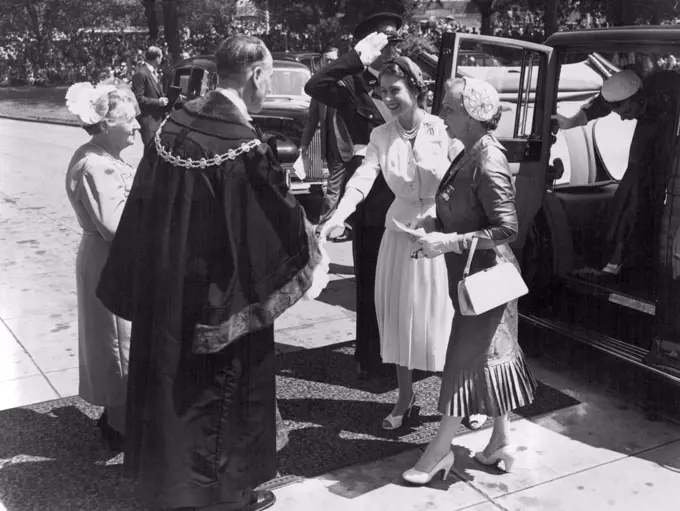 Royal Tour Melbourne Victoria. With a bright smile, the Queen steps from her car to shake the hand of the Mayor of St. Kida, Cr. W.E. Dickeson, as she arrived at the St. Kilda Town Hall for the combined women's organisations luncheon. On the right is Mrs. John Cain, wife of the Premier. March 05, 1954.