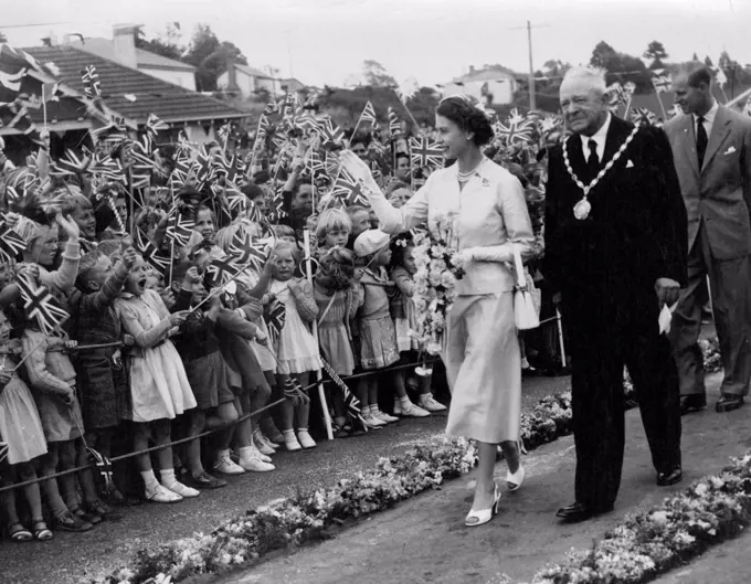 Thousands of children waving flags packed outside the railway station at Palmerston to greet Queen Elizabeth and the Duke of Edinburgh, With her Majesty is Mayor W. J. Honkins. February 10, 1954.