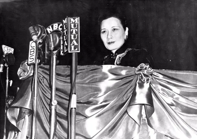 Madame Chiang Kai-Shek Addresses The American People -- Madame Chiang Kai-Shek, standing before a barrage of microphones on the speakers' stand at Madison Square Garden, addresses the thousands who appeared to honor her arrival in New York City. Her address was also heard all over America by radio. April 21, 1943.  