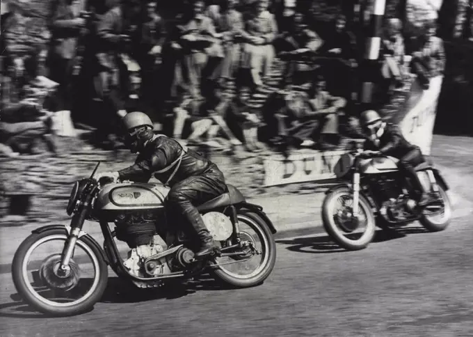 Motor Cycling "Duke" Wins Isle Of Man Race -- Geoffrey Duke riding a Norton (No.1) catching up on T. McEwen (also on a Norton) (No. 85) around the sharp corner at Governor's bridge during the race.Geoffrey Duke - "The Duke" of motor cycle racing - won the Senior International Tourist Trophy Race in the Isle of Man yesterday and smashed all his own records - by mistakes. On his second circuit of the course he misread a signal and thought he was lying third. He "burned up" the last 13 miles of the 38-mile course, touching 130 miles perhour and raised his lap record form 93.53 miles per hour to 95.22. June 9, 1951. (Photo by Paul Popper).
