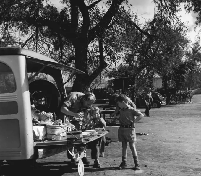 Kruger Nat. Park - People visit the Park from all over the S.A. Union, the Rhodesia's and Portuguese territory. Many come from abroad on organized tours. Pictures shows Mr. and Mrs. Foots of Edinburgh, Scotland and Cape Town with their children, Valerie and Michael, who have arrived after a 1,500 mile drive from Cape Province, and can be seen having a picnic lunch at Punda Maria camp. Mrs. Foote (background) is heating up soup). November 25, 1948. (Photo by George Rodger, Magnum).
