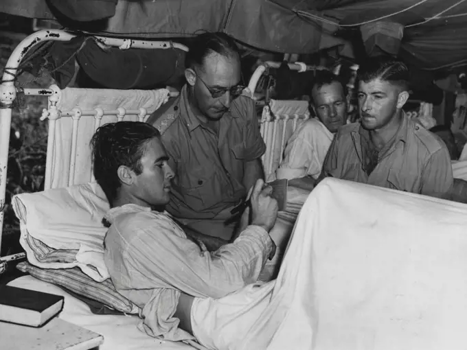 A patient at an Australian General Hospital at Lae casting his vote on the Regerendum. Caption A.J. Bushell of New South Wales is the electoral officer. August 28, 1944.