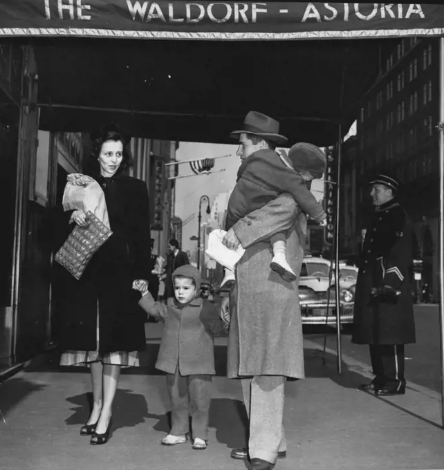 From A Cold Water Flat To The Waldorf -- Richard Earl Cox Carrier his sleeping 1½-year-old Son, Richard, Jr., As he, his wife Eleanor, and their other son, Jimmie, 2½, arrive at the Waldorf-Astoria Hotel, New York, March 14. Cox moved his family into a $12.60 a day room at the Hotel, insisting he would pay $4 of the monthly bill. The remainder. He said, would be sent to Mayor O'Dwyer because the city had not providing the Coxes with quarters in a veteran's housing project. The family was living in a $16 a month cold water flat in Brooklyn. March 14, 1948. (Photo by Associated Press Photo).
