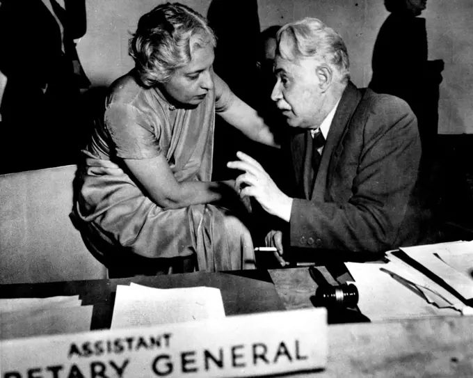 Informal U.N. Talk - Seated on the arm of a chair, Mrs. Vijaya Lakshmi Pandit, delegates from India, vonverses informally with Dr. Dmitry Z. Manuilsky, Ukrainian representative during a recent U.N. Political and security committee meeting. April 12, 1946. (Photo by Wide World Photos).