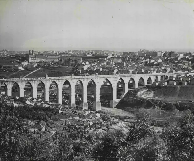 One of the most impressive sights of Lisbon is the ten-mile-long aqueduct, still carrying water into the city from the nearby hills. Three hundred feet high in some places, the picturesque structure dwarfs the suburban homes which nestle at its base. April 22, 1955. (Photo by United Press).