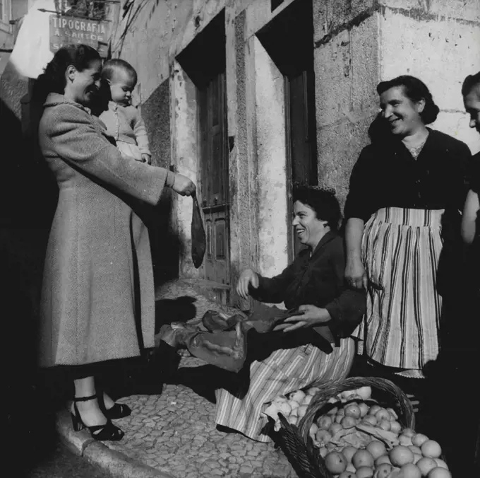 Lisbon 1952 - Fish burying in one of the typical narrow streets is enjoyable for both client and seller. February 27, 1952. (Photo by Camera Press).
