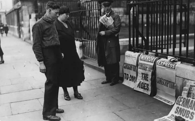 What Does *****Youth of military age studies the news paper posters announcing. Conscription, in London today (Wed). May 22, 1939. (Photo by London News Agency Photos Ltd.).