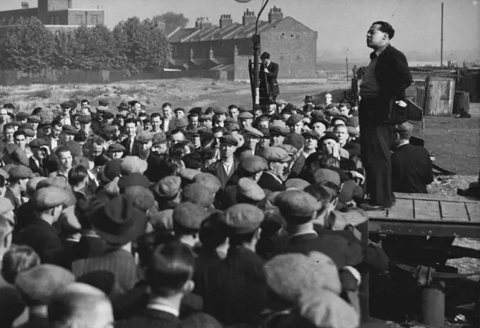 Dockers Hear 'Leader' On First Day of Emergency -- Crowd of London dockers listen to a speech by Albert Timothy, member of the unofficial 'lock out committee, at Royal.Victoria Dock to-day (Tuesday), first day of the State of Emergency regulations in the Port of London. More than 10,000 men are idle at the docks, and 112 ships are held up, owing to the refusal of the men to work the Canadian ships Beaverbrae and Argomont, which have been involved in a Canadian seamen strike. July 12, 1949. (Photo by Reuterphoto).
