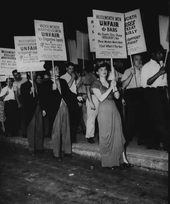 "Babs Hutton" Take off By Woolworth Pickets -- Woolworth warehouse employees and members of local 65, wholesale and warehouse union, picket the Woolworth Building in New York City, June 30, demanding re-signing of the union contract. The girl in evening gown is doing a takeoff on heiress "Babs" and men in striped, trousers and frock coats picket the pickets. July 22, 1947. (Photo by Associated Press Photo).