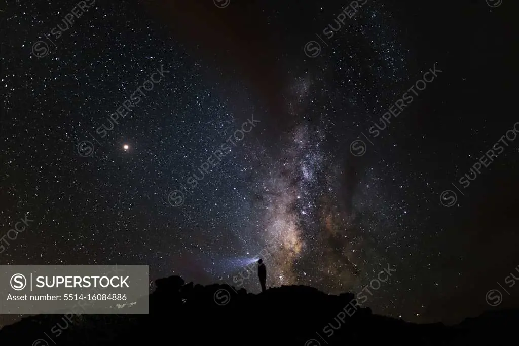 Silhouette of a mountaineer looking at the Milky Way