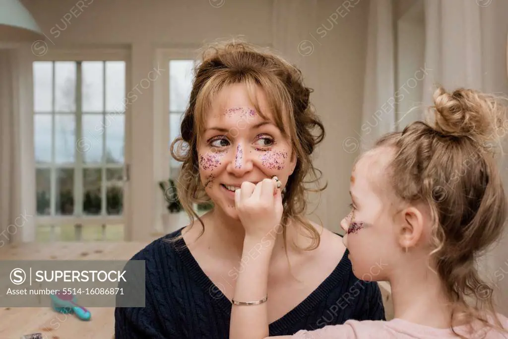 mom and daughter playing with make up and dress up at home