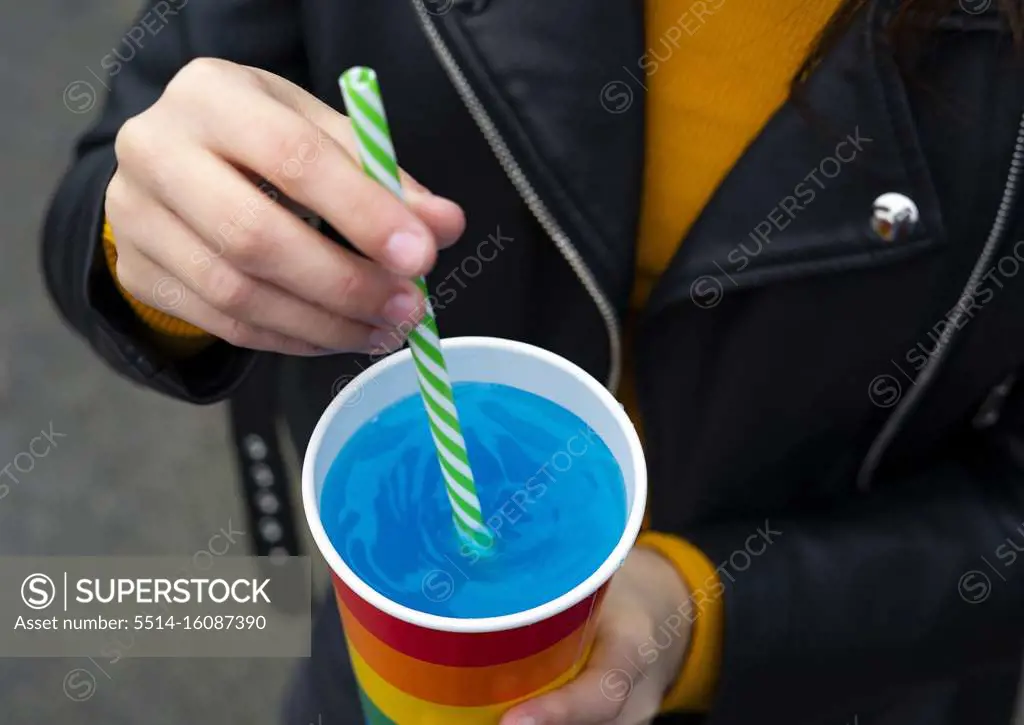Mixing a blue cocktail with a colorful straw.