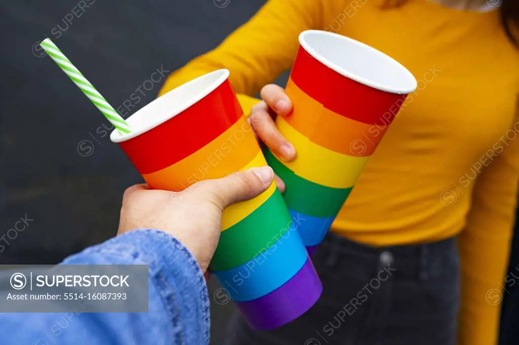 Hands toasting with rainbow pride cups at a party.