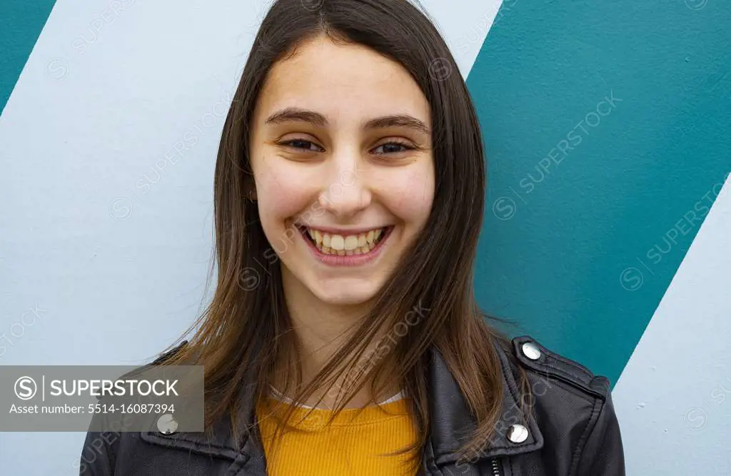 Young woman smiling on a blue background.