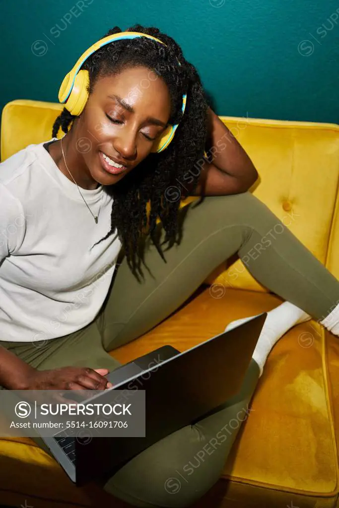 Black styled student woman listening music with yellow earphones