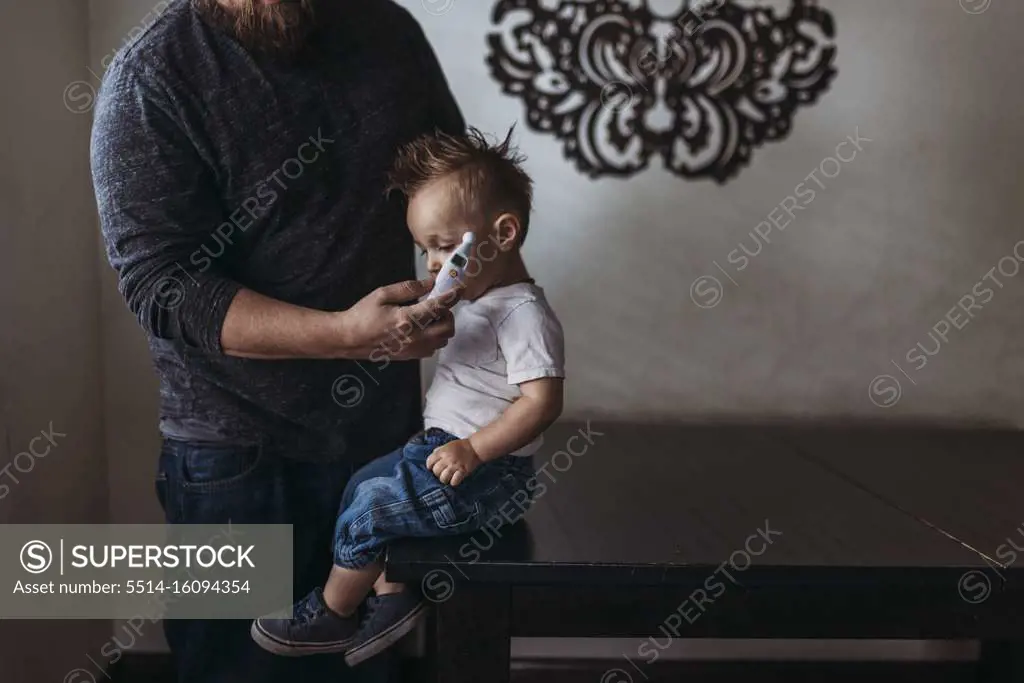 Midrange view of father taking young sons temperature at home