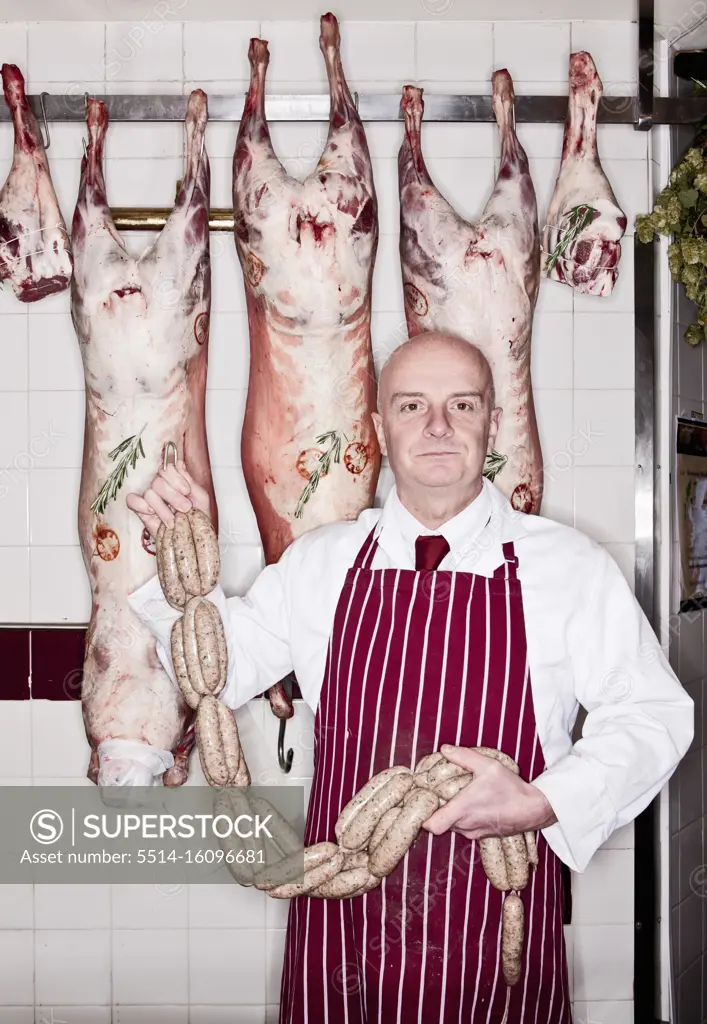 Butcher holding sausage in shop in England
